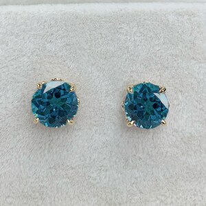 Pu&ograve; includere: Un paio di orecchini a bottone dorati con pietre rotonde di colore blu turchese.