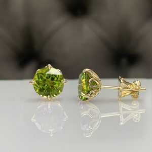 Pu&ograve; includere: Un paio di orecchini d'oro con pietre preziose rotonde verdi. Gli orecchini hanno un design delicato e decorato.