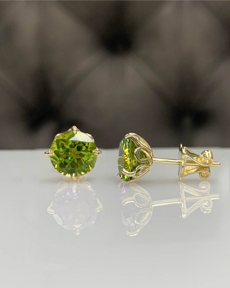Pu&ograve; includere: Un paio di orecchini d'oro con pietre preziose rotonde verdi. Gli orecchini hanno un design delicato e decorato.