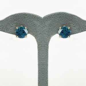Pu&ograve; includere: Un paio di orecchini a bottone in oro con una pietra preziosa rotonda blu-verde in ogni orecchino.