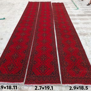 K&ouml;nnte beinhalten: Drei lange, rechteckige rote Teppiche mit komplizierten geometrischen Mustern in Schwarz und Braun. Die Teppiche liegen auf einer Betonoberfl&auml;che. Die Abmessungen betragen ca. 88 x 552 cm, 82 x 582 cm und 88 x 564 cm.