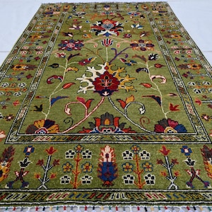 May include: A green rug with a floral pattern in shades of red, yellow, blue, and black. The rug has a border with a geometric design.