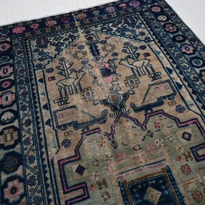 Peut inclure: Tapis ancien avec un champ central beige orn&eacute; de motifs stylis&eacute;s d'animaux et de fleurs roses et bleus. Le tapis a une bordure bleu fonc&eacute; avec des motifs floraux et des formes g&eacute;om&eacute;triques r&eacute;p&eacute;titifs. Le design du tapis est sym&eacute;trique et pr&eacute;sente des signes d'usure.