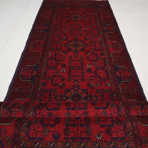 Puede incluir: Una alfombra de pasillo roja y azul con un diseño persa tradicional. La alfombra tiene un medallón central y intrincados patrones florales.