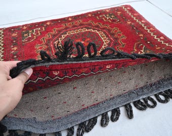 May include: A red rug with a black and white geometric pattern. The rug has a fringe border and is folded in half.