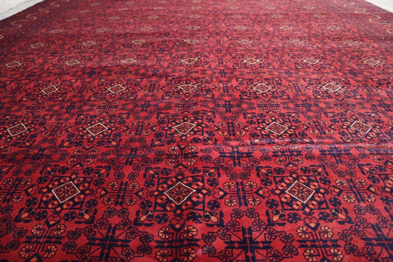 May include: A red rug with a geometric pattern in shades of blue and cream. The rug has a traditional Persian design.