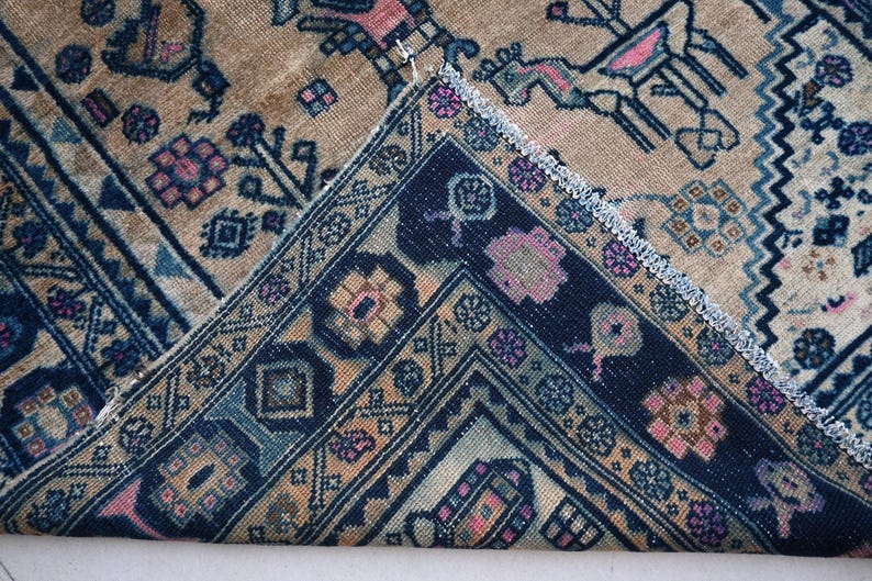 May include: Close-up of a rug with a blue and beige pattern. The rug has a fringe border and intricate geometric designs.