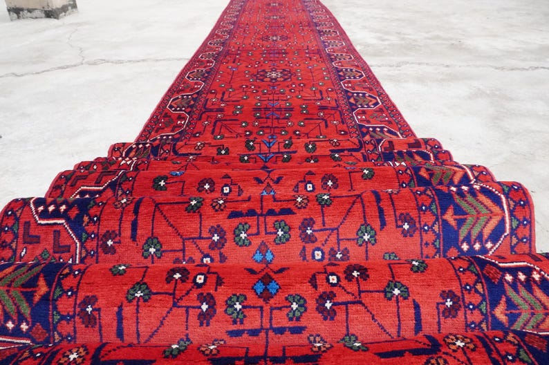 May include: A red, blue, and green patterned rug is rolled up and stacked. The rug has a traditional design with intricate details.
