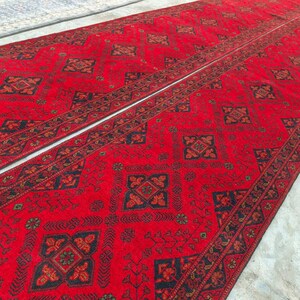 K&ouml;nnte beinhalten: Zwei rote L&auml;ufer mit aufwendigen geometrischen Mustern in Schwarz und Braun. Die Teppiche haben ein zentrales Design mit sich wiederholenden Motiven und einen detaillierten Rand. Die Teppiche sind nebeneinander platziert.