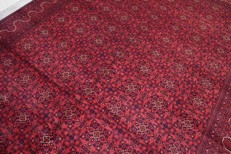 May include: A red rug with a repeating pattern of blue and white geometric shapes. The rug has a traditional Persian design.