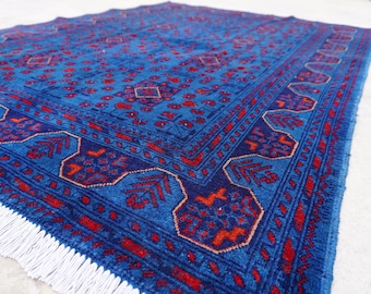 May include: A blue and red patterned rug with a white fringe. The rug has a geometric design with intricate details.