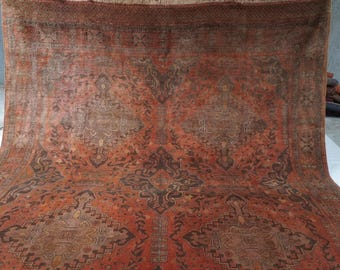 May include: A large rectangular area rug featuring a deep terracotta orange background with intricate dark brown and muted tan geometric patterns, including central diamond-shaped medallions and detailed border motifs throughout the woven surface.