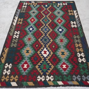 May include: A colorful rug with a geometric pattern in shades of red, green, blue, and brown. The rug has a fringe border.