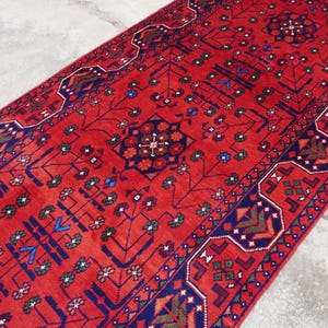 May include: A red and blue patterned runner rug with intricate floral and geometric designs. The rug has a traditional Persian style.