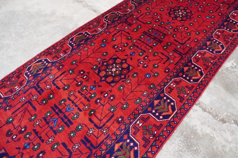 May include: A red and blue patterned runner rug with intricate floral and geometric designs. The rug has a traditional Persian style.