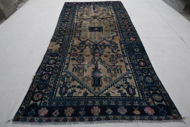 Peut inclure: Tapis rectangulaire beige et bleu marine avec un motif complexe. Le tapis pr&eacute;sente un motif central avec des motifs floraux et g&eacute;om&eacute;triques, encadr&eacute; par une bordure bleu marine avec des accents floraux. Le design du tapis est sym&eacute;trique.