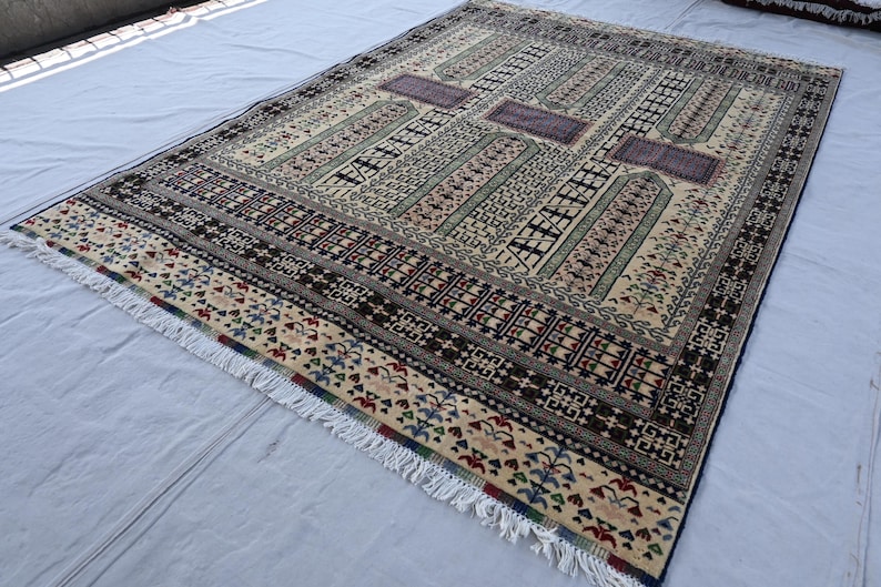 Pu&ograve; includere: Un tappeto beige, marrone e blu con un bordo a frangia. Il tappeto presenta un design geometrico con dettagli intricati.