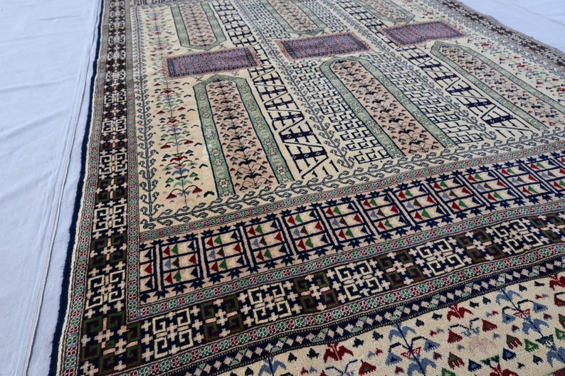 Pu&ograve; includere: Un tappeto tradizionale con sfondo crema e motivi intricati in tonalit&agrave; di blu, verde, rosso e nero. Il tappeto presenta un design geometrico con motivi ripetitivi.