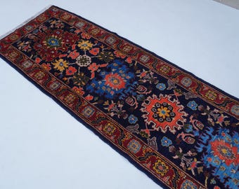 May include: A long, narrow rug with a dark blue background and intricate floral patterns in shades of red, orange, yellow, and blue. The rug has a border of red and gold.
