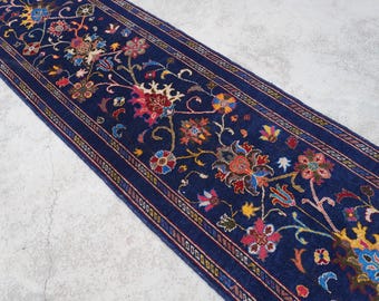 May include: A blue runner rug with a floral pattern in shades of red, yellow, and white. The rug has a border with a repeating pattern.