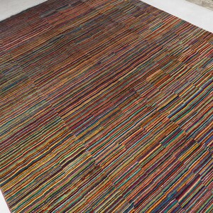 May include: A rectangular area rug featuring a dense, multi-colored striped pattern. The design consists of thin, horizontal lines in various shades of red, orange, yellow, green, blue, and purple, creating a vibrant, textured appearance across the surface.