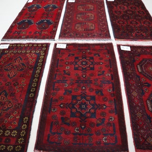 May include: Six red, blue and gold patterned rugs with a white border. The rugs are arranged in two rows of three. The rugs are all the same size and shape.