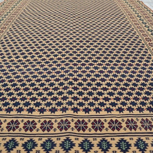May include: A beige rug with a repeating pattern of dark blue stars and a border of red, blue, and green geometric designs.