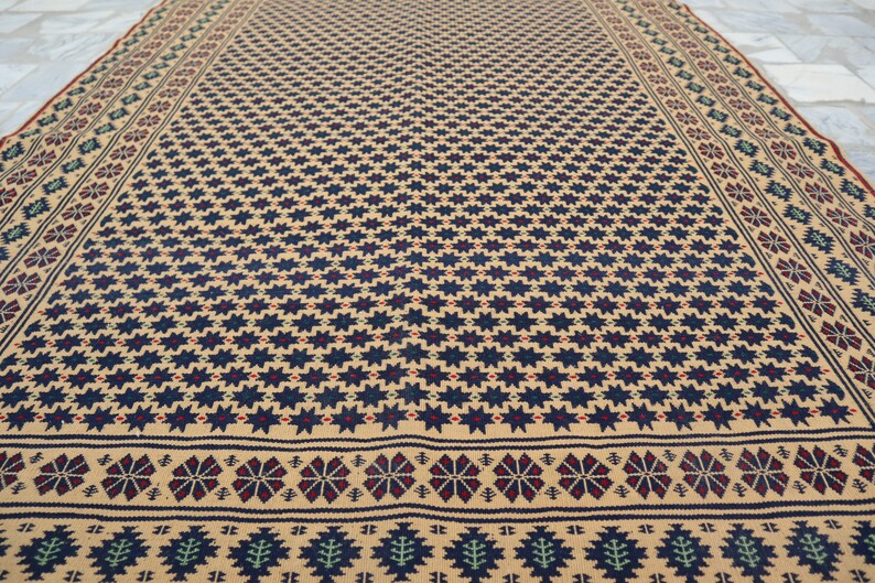 May include: A beige rug with a repeating pattern of dark blue stars and a border of red, blue, and green geometric designs.