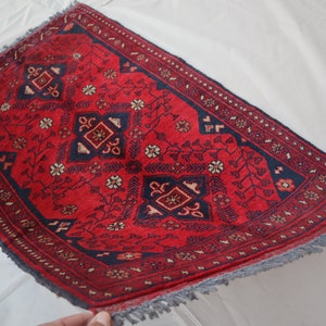 May include: A red and blue rug with a traditional Persian design. The rug has a fringe border and is made of wool.
