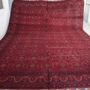 May include: A large red rug with a geometric pattern and a dark blue border. The rug has a traditional Persian design.