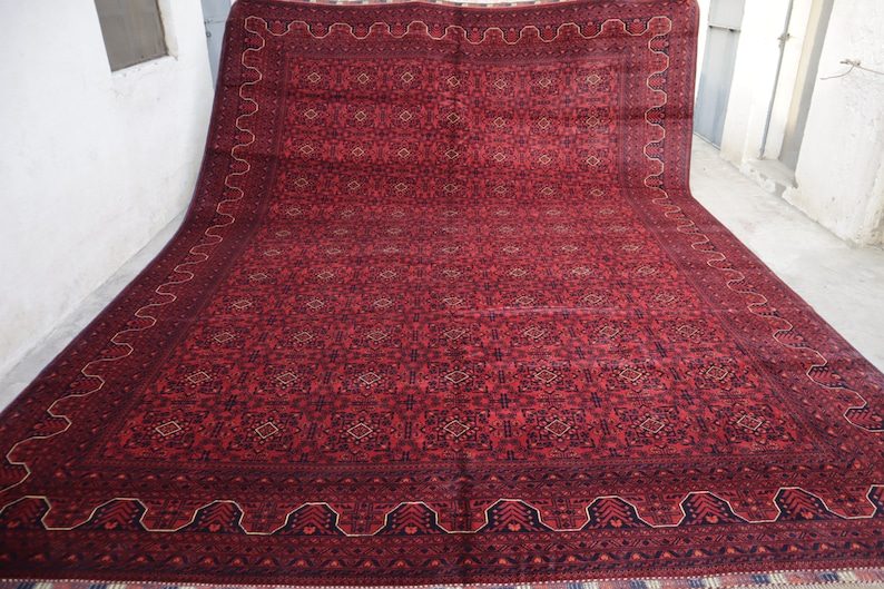May include: A large red rug with a geometric pattern and a dark blue border. The rug has a traditional Persian design.