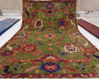May include: A green, red, and blue patterned rug with intricate floral designs. The rug has a border with a repeating pattern of red, green, and blue.