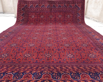 May include: A large, red and blue patterned rug with a detailed geometric design. The rug has a thick border with a repeating pattern.