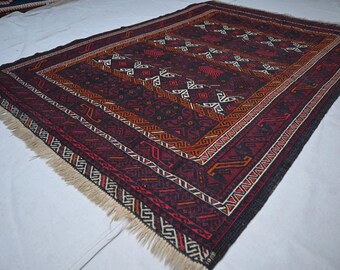 May include: Rectangular rug with a dark red and black background, featuring geometric patterns in white, orange, and red. The rug has a detailed border and fringed edges, showcasing a traditional design.