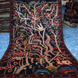 Peut inclure: Un tapis persan traditionnel avec un fond bleu foncé et des motifs complexes. Le tapis présente un motif d'arbre de vie avec des oiseaux, des animaux et des fleurs. Le tapis est tissé en laine et en soie et a un nombre élevé de nœuds.