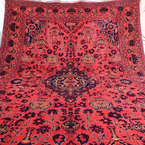 K&ouml;nnte beinhalten: Ein gro&szlig;er, roter persischer Teppich mit einem detaillierten floralen und geometrischen Muster. Der Teppich hat einen dunkelblauen Rand mit komplizierten Designs.