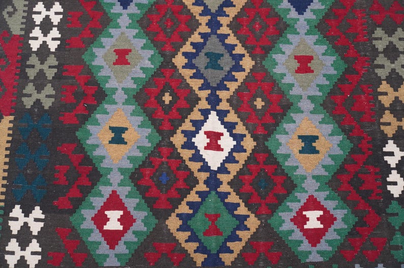 May include: A colorful rug with a geometric pattern in shades of red, blue, green, white, and brown. The pattern is made up of repeating diamond shapes.