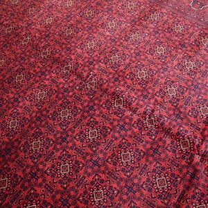 May include: Red rug with a repeating geometric pattern in black and cream.