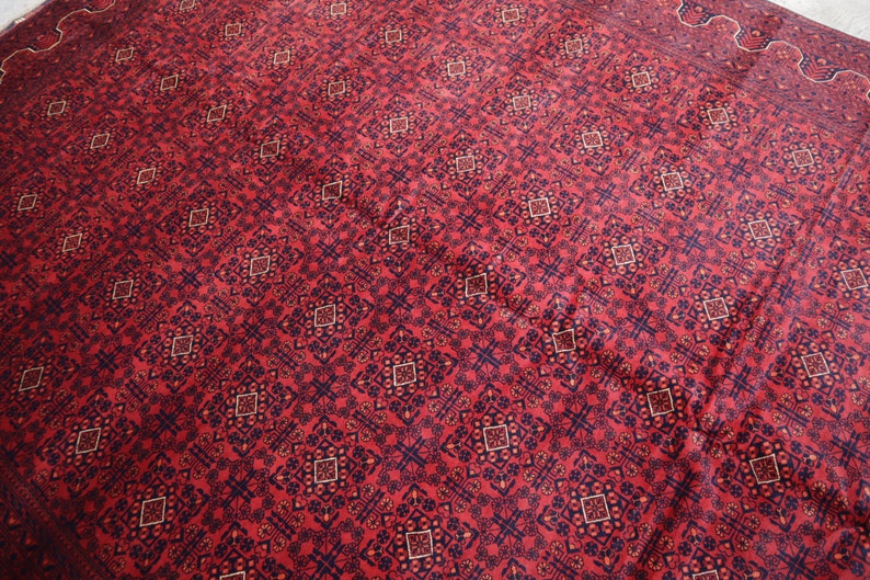 May include: Red rug with a repeating geometric pattern in black and cream.