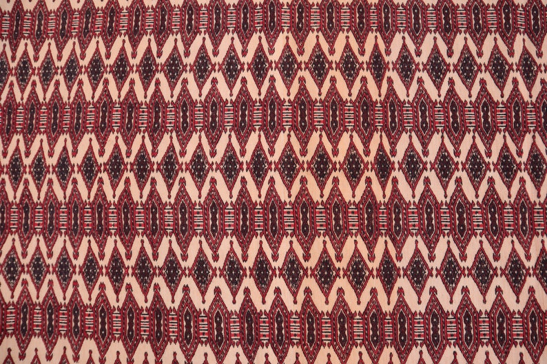 May include: A close-up of a red, black and white patterned fabric with a repeating diamond design.