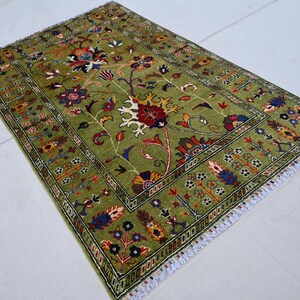 May include: A green rug with a floral pattern in shades of red, blue, and yellow. The rug has a white fringe border.