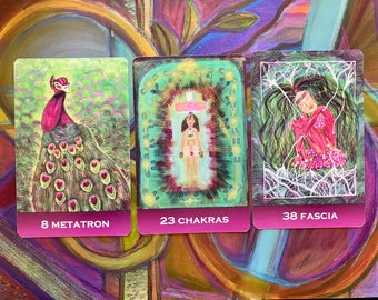 May include: Three tarot cards with pink borders and green backgrounds. The first card shows a peacock with a pink head and green and brown feathers. The second card shows a person with a crown and seven chakras. The third card shows a woman with long hair and a red dress. The cards are labeled "8 Metatron", "23 Chakras", and "38 Fascia".
