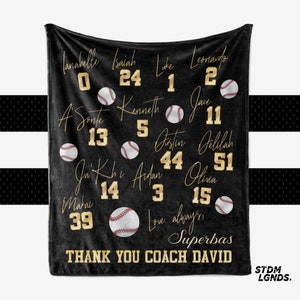 May include: Black fleece blanket with gold lettering and baseball graphics. The blanket features names and numbers of a baseball team, including "Superbas" and "Thank You Coach David".