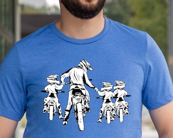 Könnte beinhalten: Ein blaues T-Shirt mit einer weißen Grafik von vier Personen, die auf Dirtbikes fahren. Die Personen tragen Helme und fahren in einer Reihe.