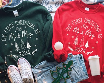 May include: Two Christmas sweaters, one green and one red, with the text "Our First Christmas as Mr. & Mrs. 2024" in white. The sweaters feature a stylized Christmas tree design.