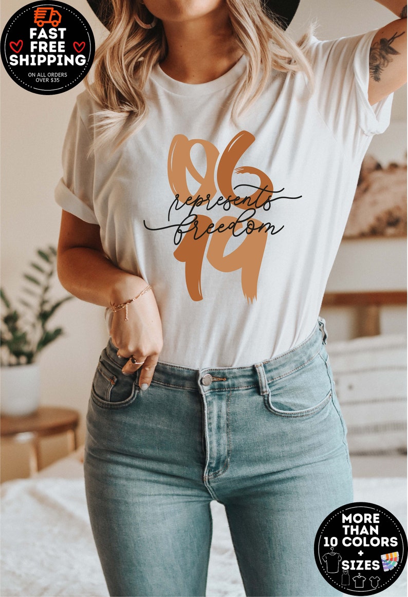 May include: Cream-colored t-shirt with the text "96 represents freedom" in brown and black. The shirt is paired with light blue jeans. The image also includes promotional graphics for fast, free shipping and more color and size options.