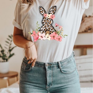 May include: White t-shirt with a graphic of a leopard print bunny with pink flowers. The shirt is available in more than 10 colors and sizes.