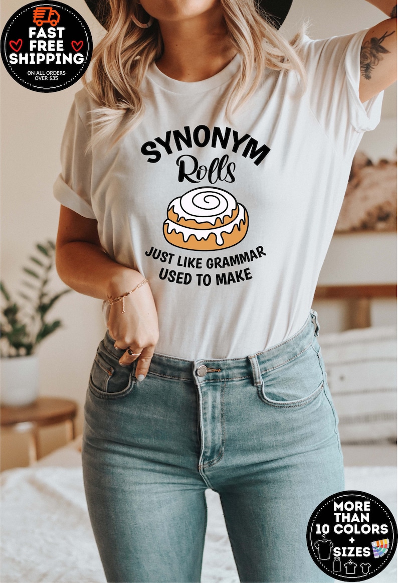 K&ouml;nnte beinhalten: Wei&szlig;es T-Shirt mit einer schwarzen Grafik, auf der "Synonym Rolls" steht, darunter ein Cartoon-Zimtschnecken. Der Text unter der Zimtschnecke lautet "Just like grammar used to make."