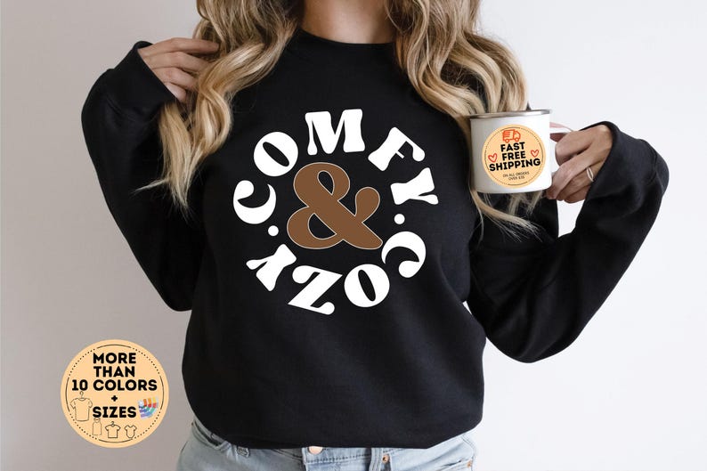 May include: Black sweatshirt with white text that reads "Comfy & Cozy" in a retro font. The text is inside a circle with a brown ampersand in the centre.