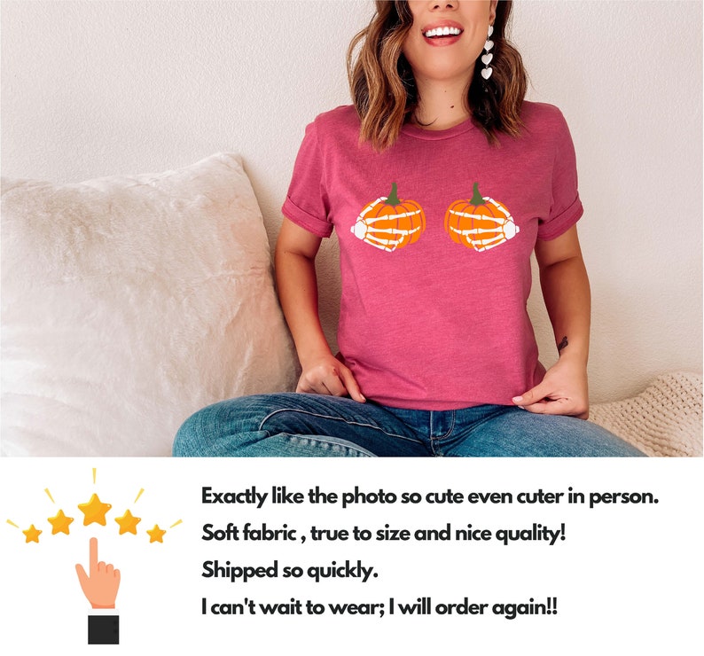 May include: A pink t-shirt with a graphic of two orange pumpkins with white skeleton hands. The pumpkins are positioned as if they are breasts.